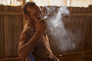 Man takes a break from discussing community nutrition by making his own cigar and smoking it to the side. 